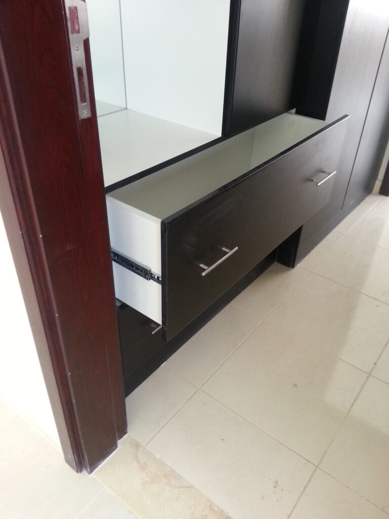 In this Abu Dhabi apartment whole house custom project, the storage cabinet features silver metal handles and a sliding track system, with an integrated mirror, combining functionality and modern design.