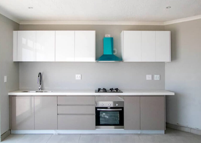 Sleek and modern kitchen cabinets for Ongwe Apartment featuring white and beige tones.