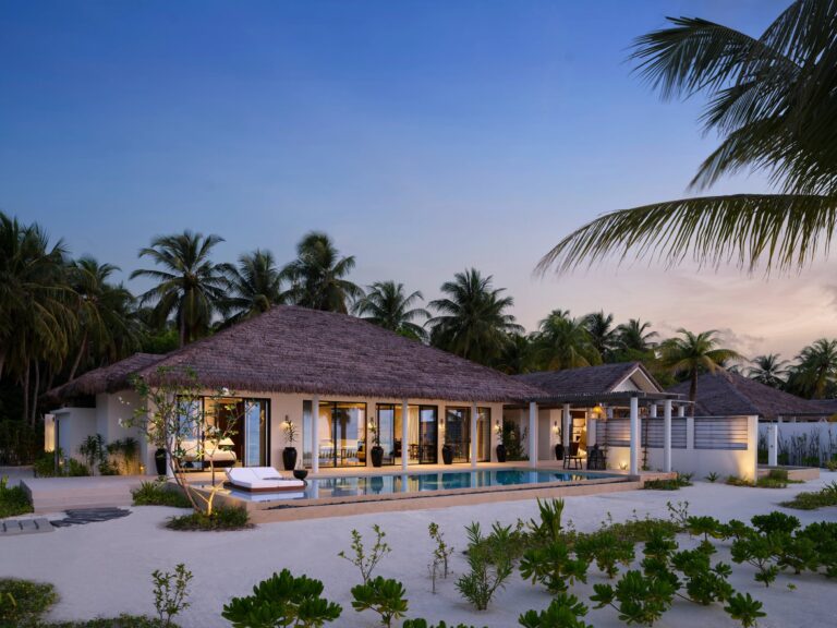 tropical villa exterior with beachfront pool and palm trees at sunset