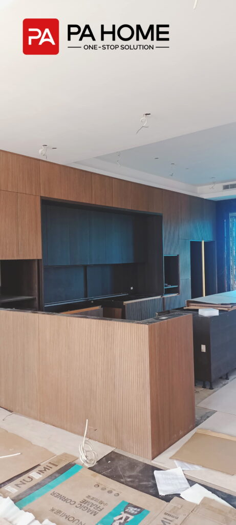 Renovasi Rumah di Indonesia dengan Kabinet Dapur dan Lemari Pakaian Kamar Tidur yang Dibuat Sesuai Pesanan 10 Kabinet dapur kustom motif kayu modern dengan pulau dapur bergaris dan kabinet gelap dalam proyek renovasi di Indonesia.