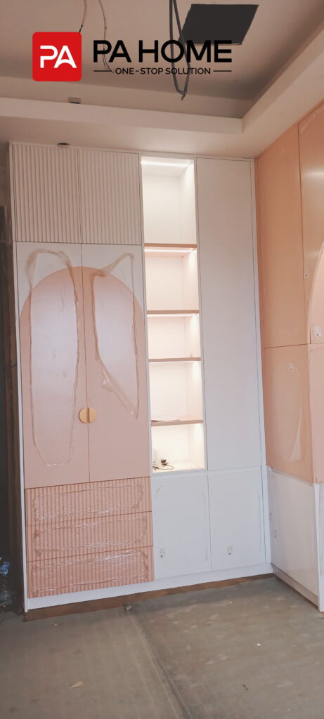 Renovasi Rumah di Indonesia dengan Kabinet Dapur dan Lemari Pakaian Kamar Tidur yang Dibuat Sesuai Pesanan 7 Lemari pakaian anak-anak custom dengan pintu pink, rak terbuka yang menyala, dan lemari penyimpanan putih di Indonesia.