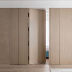 A natural wood-colored flush door seamlessly integrated into the wall panels, offering a sleek, minimalist design that blends effortlessly with the surrounding space. Perfect for wholesale interior door projects.