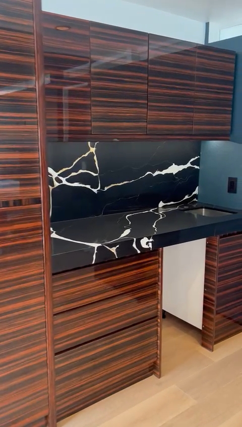 Custom office cabinet design with striped wood finish and marble countertop in an American office.