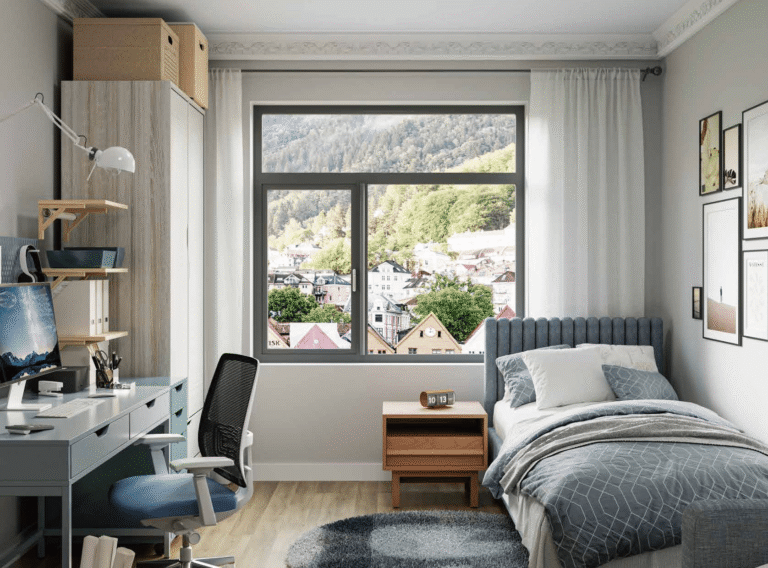 A cozy, modern children's or guest bedroom featuring a dark-framed aluminium casement window with multiple vertical and horizontal mullions, offering a view of a town nestled in the mountains.