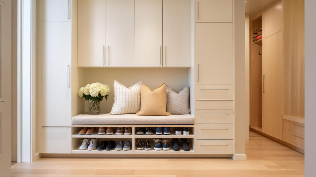 Top Custom Furniture Trends in Indonesia 2 PA HOME built-in entryway cabinet system featuring hidden shoe storage, integrated bench seating, and overhead cabinets, designed for compact apartments with a clean and organized entrance layout.