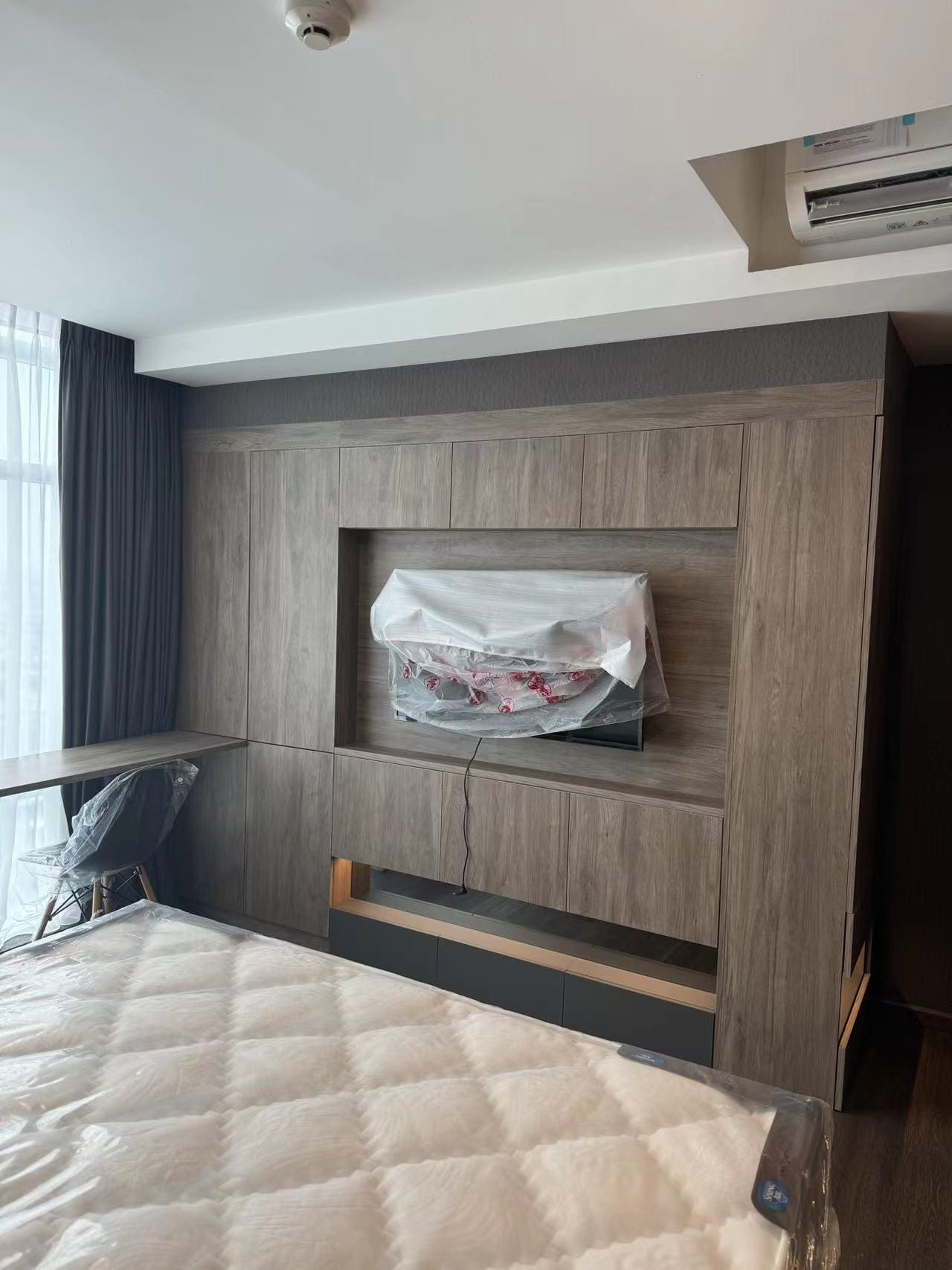 Medan Manhattan Apartment Renovation in Indonesia 3 Medan apartment renovation bedroom with custom wood TV wall cabinet and integrated storage.