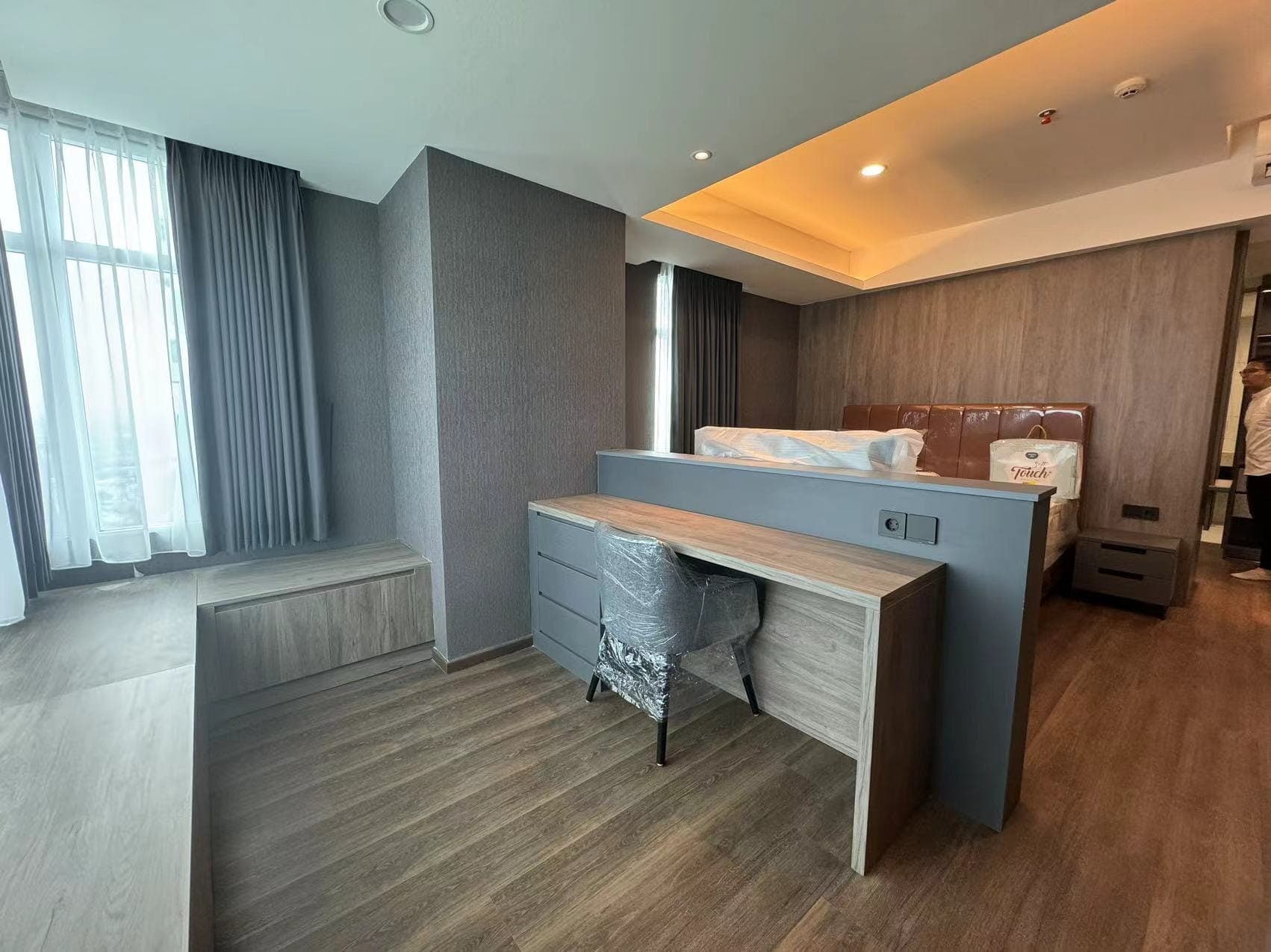 Medan Manhattan Apartment Renovation in Indonesia 16 Bedroom partition desk and storage cabinet in Medan apartment with wood finish and compact layout.