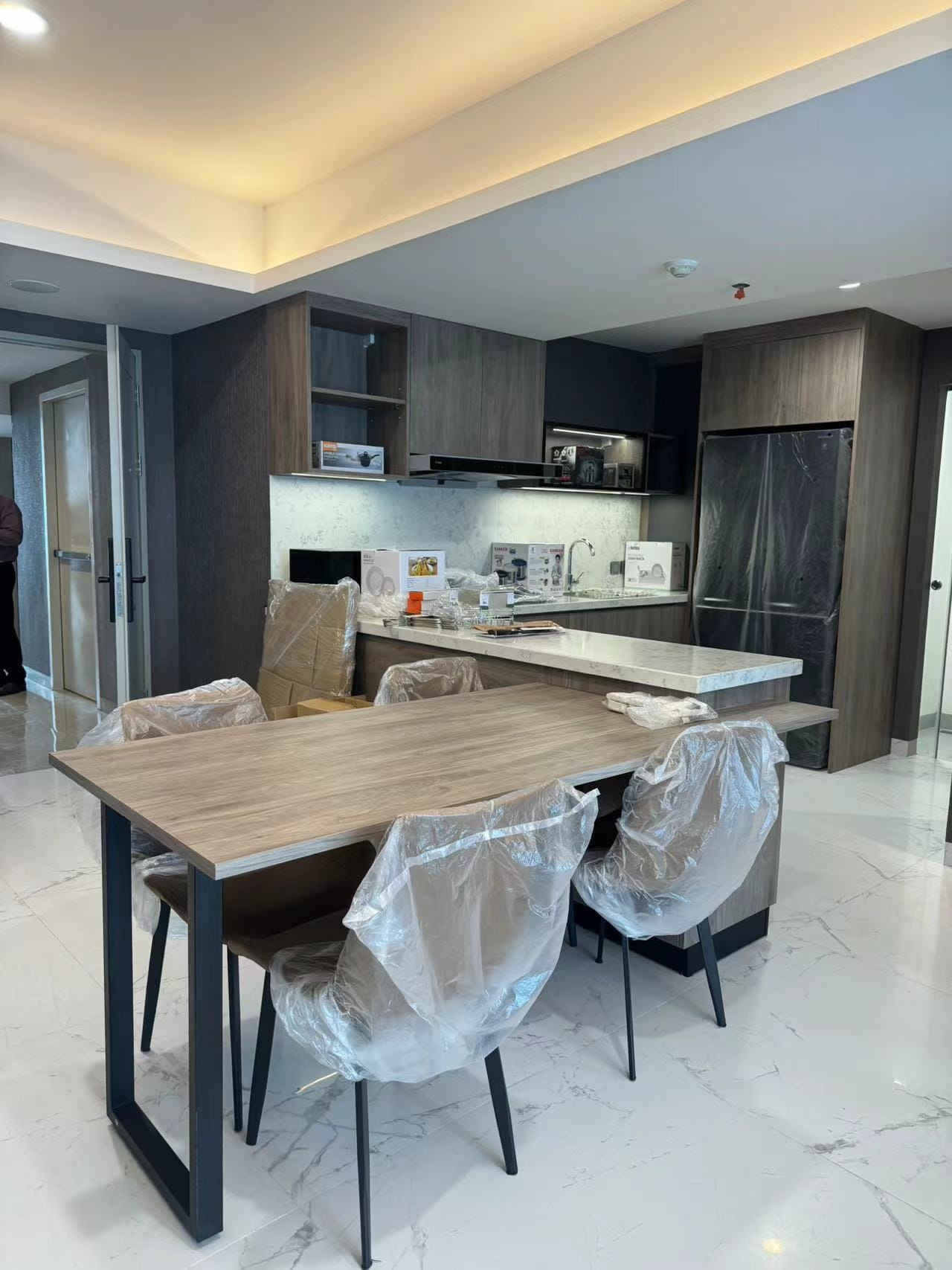 Medan Manhattan Apartment Renovation in Indonesia 9 Medan apartment renovation open kitchen and dining area with custom wood cabinets and marble-look island.
