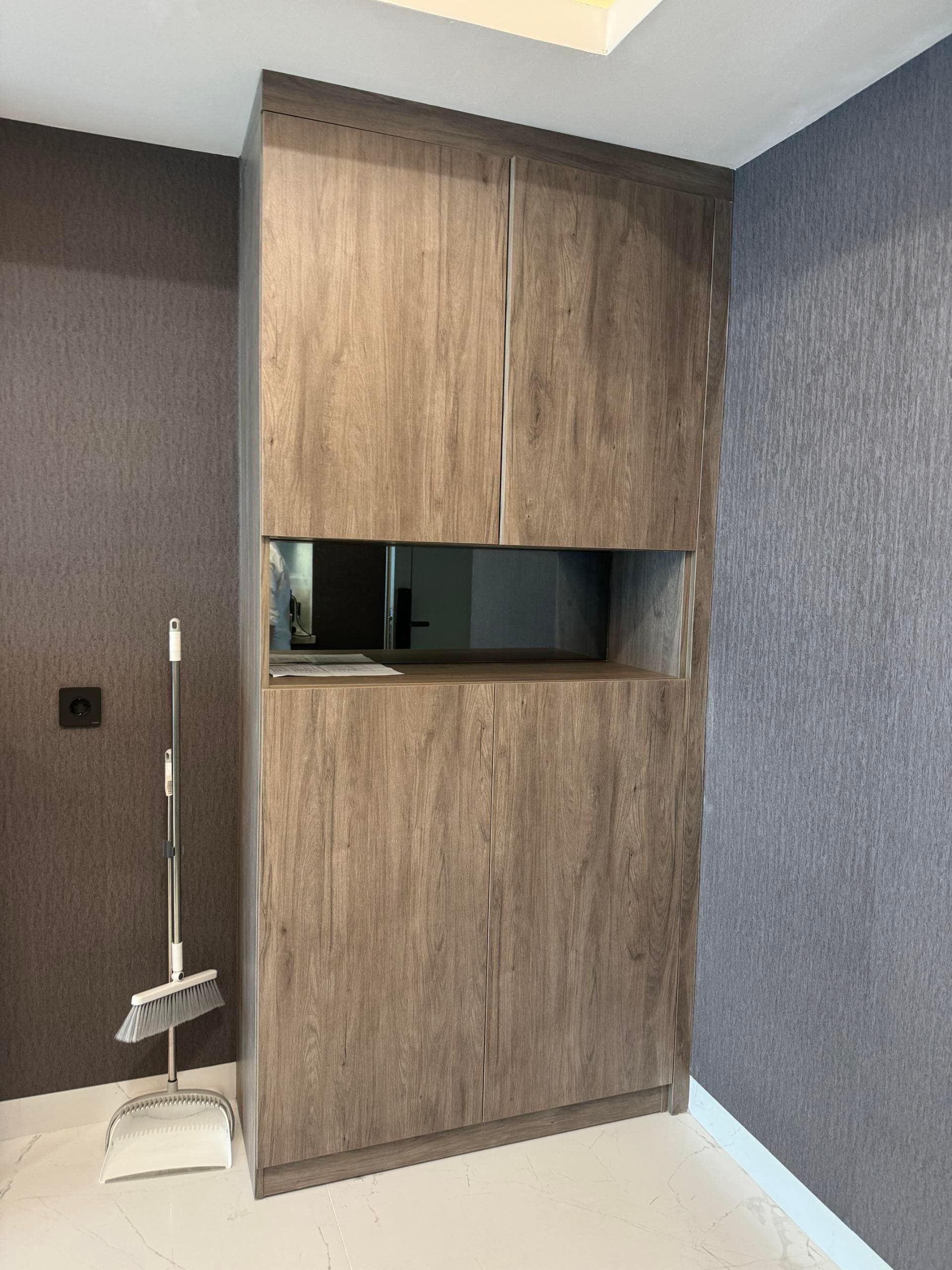 Medan Manhattan Apartment Renovation in Indonesia 14 Tall wood storage cabinet for Medan apartment renovation with open display section and concealed storage.