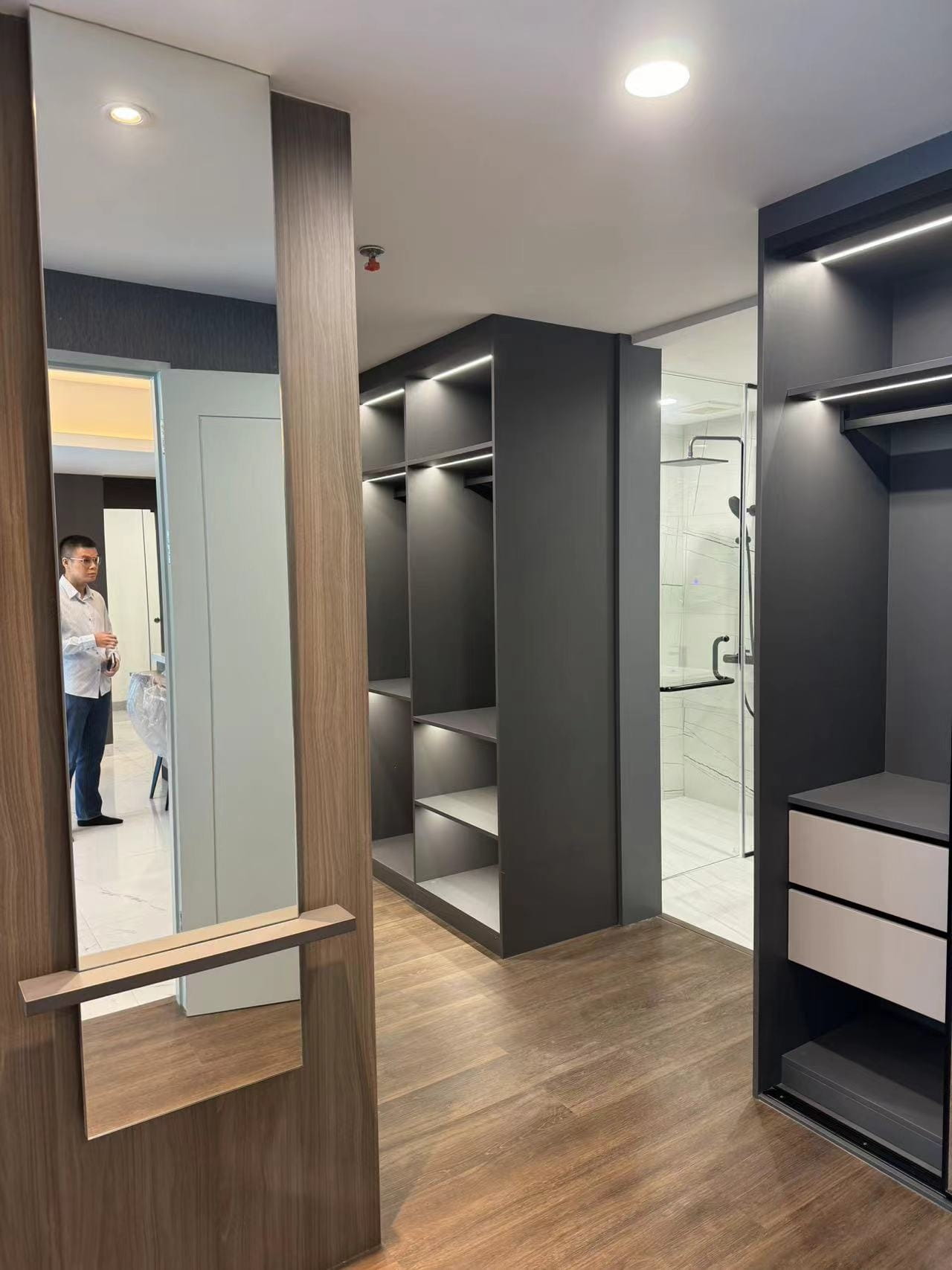 Medan Manhattan Apartment Renovation in Indonesia 10 Medan apartment walk-in closet with mirror, open wardrobe storage, drawers, and wood flooring.