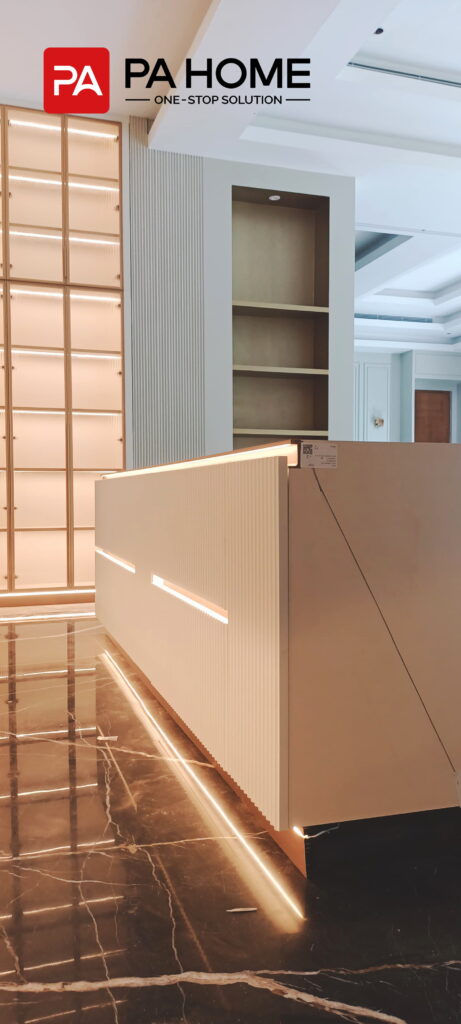 Renovasi Rumah di Indonesia dengan Kabinet Dapur dan Lemari Pakaian Kamar Tidur yang Dibuat Sesuai Pesanan 3 Tampilan dekat dari meja dapur tengah berwarna putih dengan desain berlekuk, pencahayaan LED terintegrasi, dan lemari khusus.