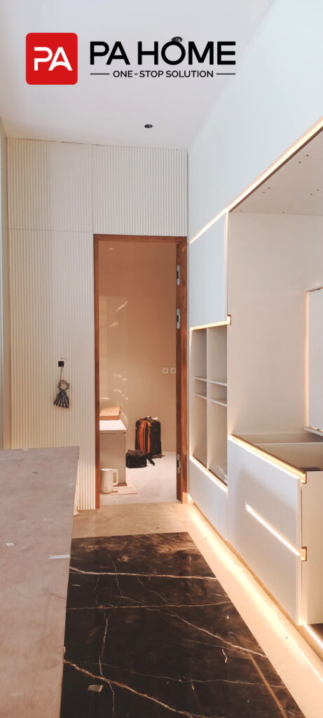 Renovasi Rumah di Indonesia dengan Kabinet Dapur dan Lemari Pakaian Kamar Tidur yang Dibuat Sesuai Pesanan 4 Kabinet dapur putih custom dengan bagian depan beralur, pencahayaan terintegrasi, dan penyimpanan tinggi dalam renovasi rumah di Indonesia.