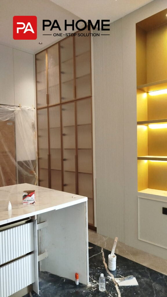 Renovasi Rumah di Indonesia dengan Kabinet Dapur dan Lemari Pakaian Kamar Tidur yang Dibuat Sesuai Pesanan 2 Lemari dapur custom dengan penyimpanan display kaca bercahaya dan kitchen island putih di Indonesia.