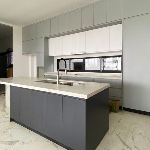 Modern kitchen cabinet design with a sleek combination of light gray and dark gray cabinets in an Indonesian home.