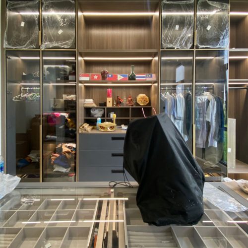 Modern walk-in closet design in an Indonesian home with open shelving and glass-fronted cabinets.