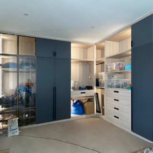 Modern wardrobe design in an Indonesian home with a mix of dark and light cabinetry and open shelving.