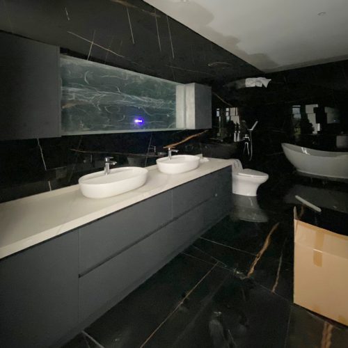 Modern bathroom vanity with dual sinks and sleek black marble finishes in an Indonesian home.
