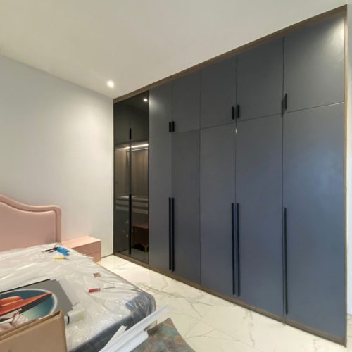 Modern bedroom wardrobe design in an Indonesian home with sleek dark cabinets and minimalistic black handles.