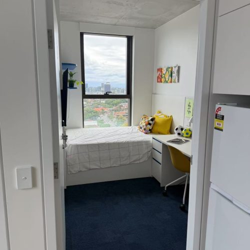 Student bedroom in Sydney with custom furniture and an awning window offering city views.