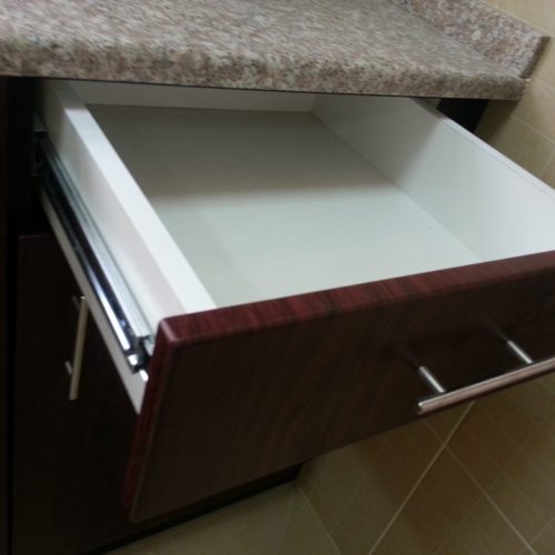 In this Abu Dhabi whole house custom project, the cabinets feature a cherry wood veneer with silver metal handles and track-mounted pull-out drawers, offering both elegance and functionality.