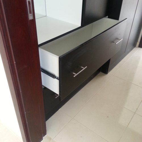 In this Abu Dhabi apartment whole house custom project, the storage cabinet features silver metal handles and a sliding track system, with an integrated mirror, combining functionality and modern design.