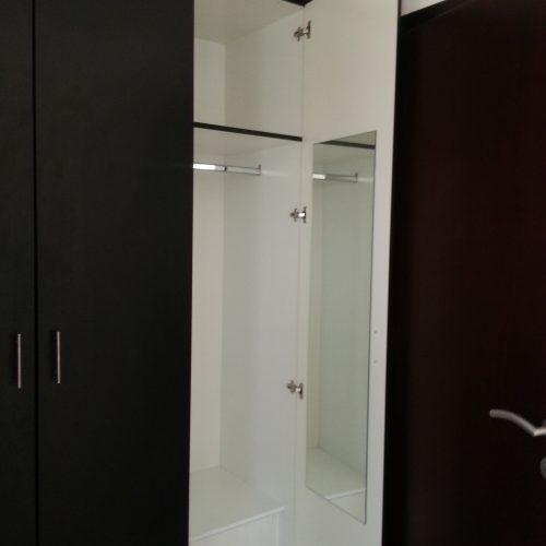 In this Abu Dhabi apartment whole house custom project, the custom black wardrobe features integrated mirrors on the cabinet doors, offering both convenience and a sleek, modern design.