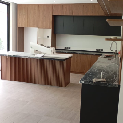 marble topped slatted wood island with integrated sink under walnut and black cabinetry
