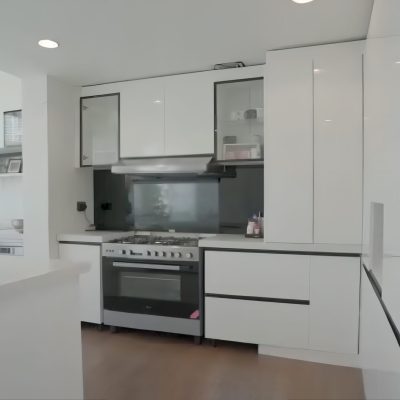 A modern-style kitchen featuring white cabinets with a smooth surface, complemented by a large narrow-framed window, adding natural light and elegance to the space.