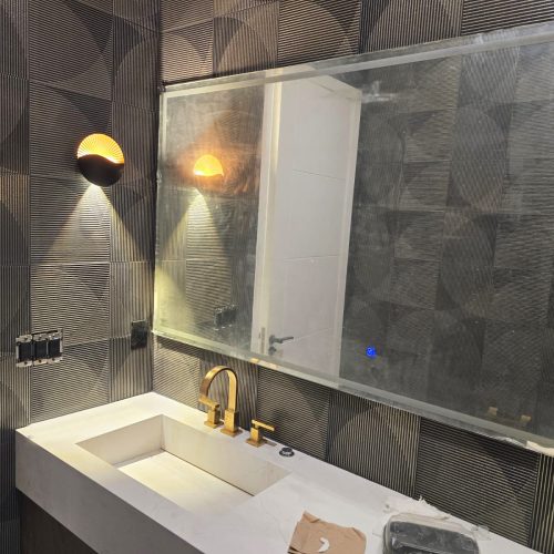 Custom bathroom vanity with gold fixtures and geometric tile wall.