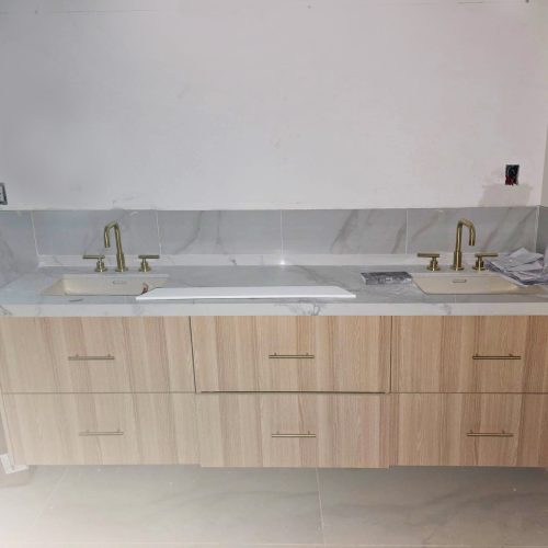 Custom double vanity in a bathroom with floating wood cabinet and marble countertop.