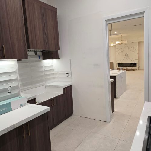 Custom kitchen with walnut cabinetry and marble countertops in an open-plan layout.