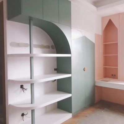 A green-and-white two-tone wardrobe and shelving unit combination, paired with a pink wall cabinet and a white desk, creating a vibrant and functional space.