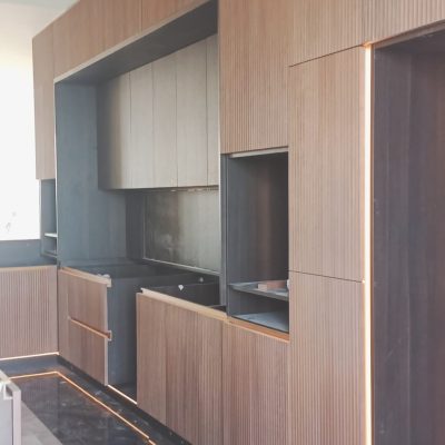 In this Indonesia full house custom project, the custom natural wood-colored cabinets feature raised vertical stripes and LED edge lighting, adding a modern and stylish touch to the space.