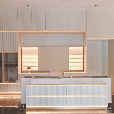 The custom floating white cabinets in this project have no frames or door handles, featuring raised vertical stripes and LED edge lighting, creating a sleek and modern aesthetic.