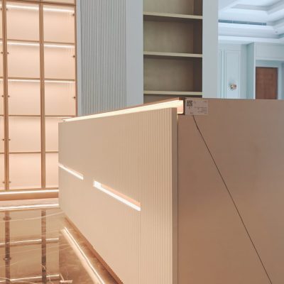 A white floating kitchen island with LED lighting, complemented by a display cabinet on the adjacent wall featuring glass doors and built-in lighting, creating a sleek and illuminated kitchen space.