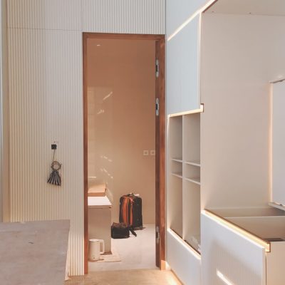 Another angle of the white custom cabinets featuring raised vertical stripes and LED lighting, showcasing a minimalist and modern design.