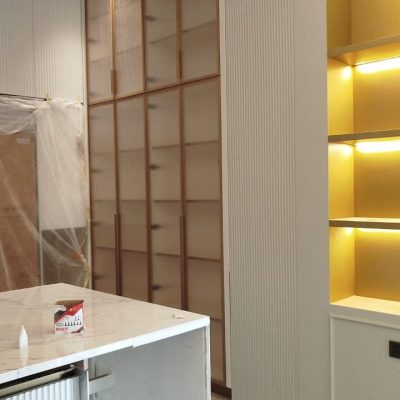 The open storage cabinet next to the kitchen island, equipped with lighting, serves as a functional display shelf while adding a stylish and organized touch to the space.