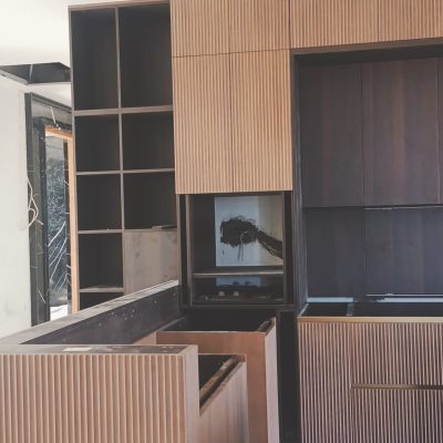 Another angle of the custom natural wood-colored cabinets in this project, highlighting the raised vertical stripes for a more detailed view of the design.
