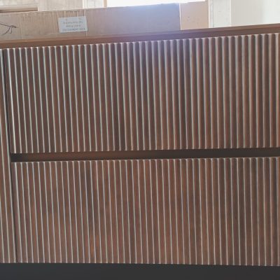 A custom natural wood-colored kitchen island featuring raised vertical stripes and LED light slots, combining functionality with modern design elements.