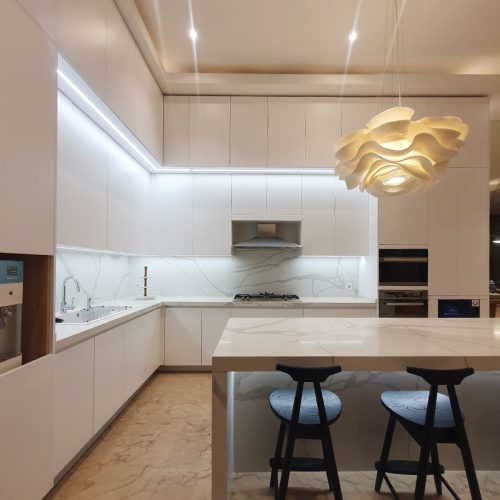 Modern Indonesian kitchen with custom kitchen cabinets, sleek white finishes, and stylish lighting.