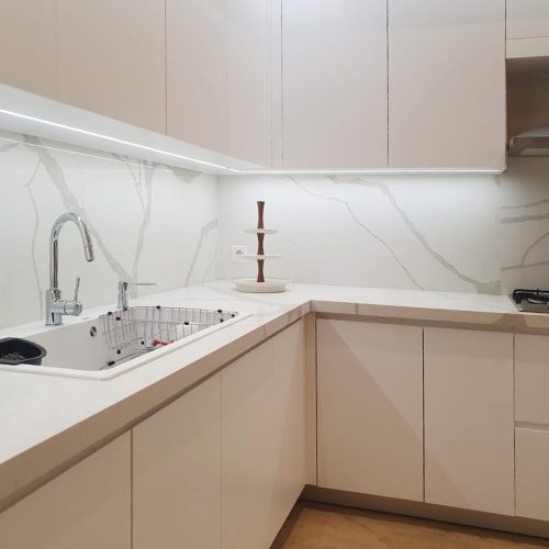 Modern Indonesian kitchen featuring a white kitchen wash basin with marble countertop and sleek cabinetry.