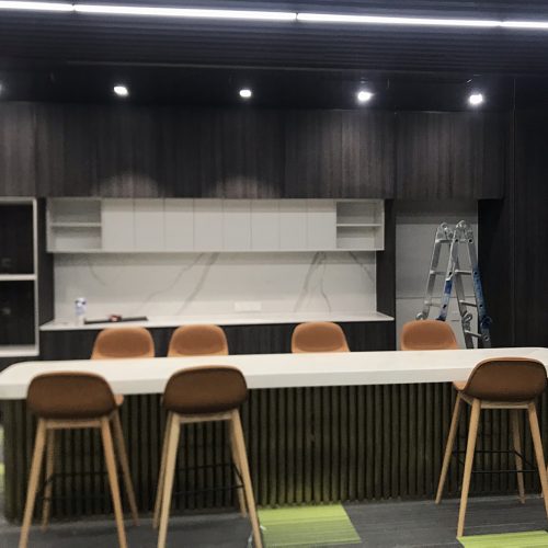 office bar cabinet with white stone countertop and stools in Indonesian workspace