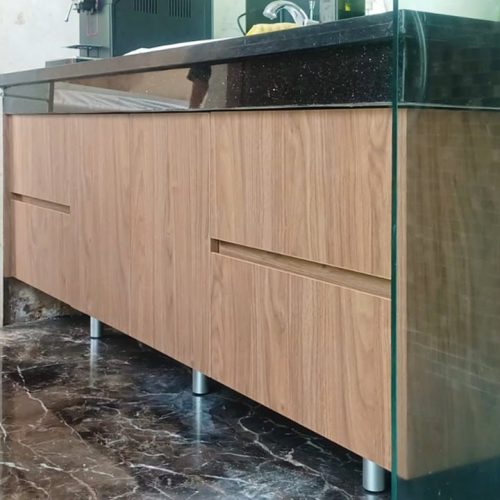 Modern bathroom vanity with wood finish and black countertop, featuring a sleek design and spacious storage.