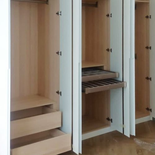 Custom wardrobe with minimalist design and sleek white finish, featuring integrated handles and modern lighting.