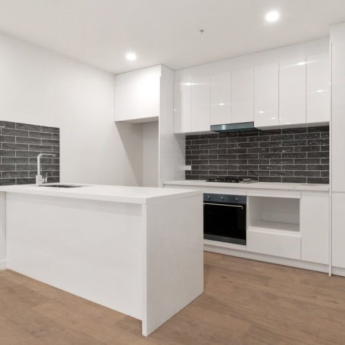 Australia Parkview Apartment Custom Cabinets Project detailed view of kitchen with white island and dark backsplash