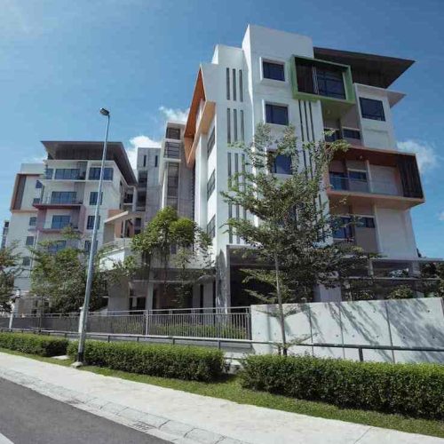 Multi‑story condominium exterior under clear sky on Kuching residential street