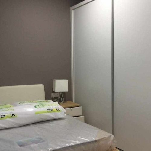 Sliding wardrobe doors beside bed with minimalist nightstand in Kuching apartment whole house custom bedroom