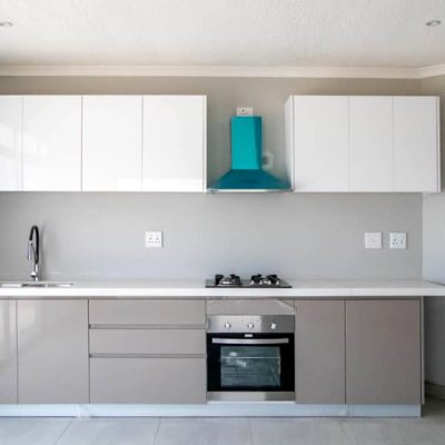 Sleek and modern kitchen cabinets for Ongwe Apartment featuring white and beige tones.
