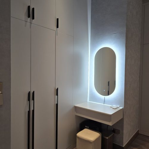 White flush-panel wardrobe with LED-backlit oval vanity mirror and floating dressing table