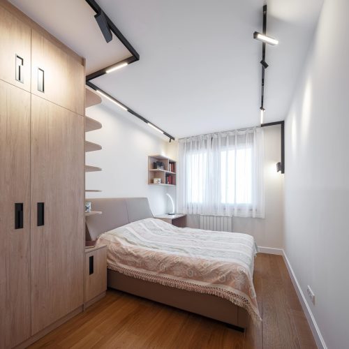 Cozy bedroom with built-in shelves and soft lighting in the Zemun stan apartment whole house custom project.